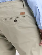 Pantalón de vestir marrón, de corte recto, con bolsillos laterales y traseros. Se ajusta a la cintura con cinturón de cuero marrón.