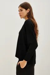 Sweater de punto negro con cuello redondo y mangas largas. Presenta un detalle bordado con lentejuelas en forma de hojas y flores en el hombro derecho.