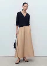 Jersey de punto fino color negro, con cuello en pico y manga larga. Presenta un diseño recto y minimalista.