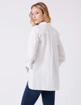Camisa blanca de algodón con corte clásico y silueta oversize, cuello con solapa y botones ocultos. Mangas tres cuartos con terminación doblada y tajo. Laterales con tajo y botones funcionales. Largo de espalda mayor al largo delantero. Espalda con canesú y pliegue central.