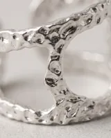 Anillo de acero quirúrgico ajustable con diseño ancho y textura punteada, que presenta una abertura geométrica central.