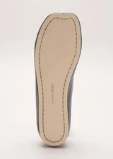 Zapato plano tipo chatita, de color negro, confeccionado en piel de ovino con diseño minimalista y puntera cuadrada.