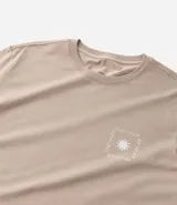 Remera masculina de algodón color beige, modelo comfort, con cuello redondo y manga corta. Presenta un pequeño estampado cuadrado en el pecho con un diseño de sol estilizado.