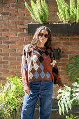 Sweater tejido de algodón con diseño de rombos multicolor en tonos marrones, azul y rojo. Presenta una silueta oversize, cuello redondo y mangas largas abullonadas con puños ajustados.