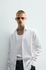 Camisa de corte slim fit confeccionada en tejido de algodón, con cuello italiano, manga larga con puños abotonados y cierre frontal de botones.