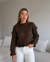 Sweater artesanal de punto en lana merino color marrón, con diseño de volados en hombros, puños y cintura, manga larga y cuello redondo alto.