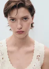 Top de crochet color crudo, sin mangas, con cuello redondo y diseño floral translúcido.