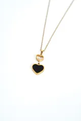 Collar dorado de cadena fina con un dije doble en forma de corazón, compuesto por un corazón pequeño hueco y un corazón grande esmaltado en negro con borde dorado.