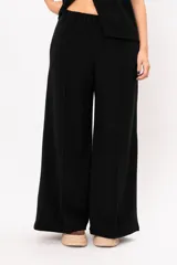 Pantalón de corte ancho y tiro alto, confeccionado en tejido de punto color marrón. Presenta cintura elástica y costuras verticales decorativas en el frente de cada pierna.