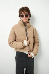 Campera puffer corta color beige de nylon, con cuello alto, cierre frontal y bolsillos laterales con cierre.