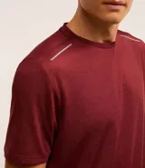 Remera deportiva masculina de manga corta con cuello redondo, confeccionada en tejido técnico con tecnología Dry para mayor transpirabilidad. Presenta detalles reflectantes en los hombros y un diseño liso en color verde melange.