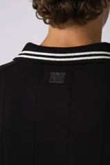 Remera de corte oversize color negro, con cuello redondo y detalle de costura en forma de X en el frente.