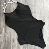 Traje de baño entero negro con escote asimétrico y tirantes blancos trenzados que se cruzan en la espalda.