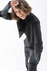 Chaqueta negra con cuello solapa, corte irregular y mangas largas con apliques de strass.