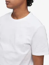 Remera blanca de algodón con cuello redondo y mangas cortas. Presenta un pequeño monograma bordado en el pecho.