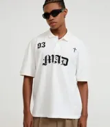 Remera de corte boxy y manga corta, confeccionada en algodón. Presenta cuello polo, estampa frontal con el texto '93 MAD' y un diseño de cruz pequeña. Posee un estilo urbano y holgado.