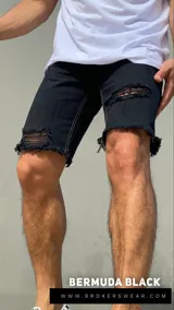 Bermuda de jean negra con roturas y terminación desflecada.