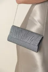 Cartera tipo sobre de lurex plateado con diseño frontal plisado. Incluye una cadena metálica fina para usar colgada al hombro.