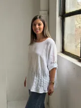 Blusa de lino color blanco, de corte amplio, con escote redondo y mangas tres cuartos con presillas para arremangar.