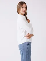 Camisa de crepe color beige con cuello clásico, cierre frontal con botones y dos bolsillos aplicados en el pecho.