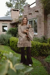 Sweater negro de lana merino con silueta amplia y relajada. Presenta mangas acampanadas con volumen, decoradas con volados de lino y terminaciones de flecos en los puños y en el ruedo.