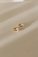 Par de aros tipo argolla dorados de acero quirúrgico, con una piedra natural de color gris translúcido colgando de cada uno.