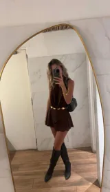 Vestido corto marrón oscuro con escote halter profundo y drapeado tipo cascada en el busto. La falda es corta con capas superpuestas y volados.