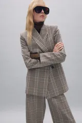 Blazer de cuello solapa y manga larga con diseño de cuadros. Presenta cierre frontal cruzado con botones.