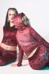 Conjunto de buzo y pantalón de terciopelo rojo con estampado animal print negro. El buzo es de corte ajustado, con capucha y cierre frontal. El pantalón es de corte acampanado y tiene un aplique de estrella de strass en la parte trasera.