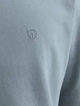 Polo de hombre confeccionado en tejido piqué de algodón, con cuello clásico, cierre frontal de botones y manga corta. Presenta un diseño liso en color azul grisáceo con un pequeño detalle bordado en el pecho.