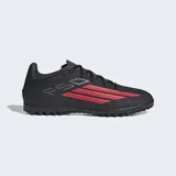 Championes de fútbol Adidas F50 Club para pasto artificial, color negro con detalles en rojo. Presentan exterior sintético Fiberskin con líneas 3D para un mejor toque de pelota y tecnología Sprintgrid. Suela de caucho diseñada para brindar agarre en giros y cortes rápidos.
