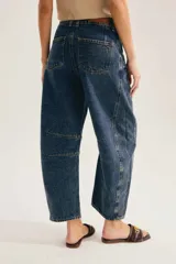 Jean barrel de tiro alto en denim azul con lavado desgastado, silueta curva y costuras decorativas a la altura de la rodilla.