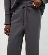 Pantalón sastre de corte wide leg en tejido crepé color marrón chocolate. Presenta una silueta recta y fluida, con cintura elástica y lazo ajustable para un calce cómodo.