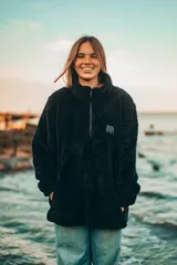 Buzo negro de polar con cierre parcial y logo de la marca bordado en el pecho.