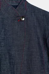 Blazer de manga corta confeccionado en lino, color azul marino, con cuello alto, cierre cruzado con un botón y pespuntes en contraste de color rojo. Cuenta con hombreras y bolsillos delanteros ribeteados.