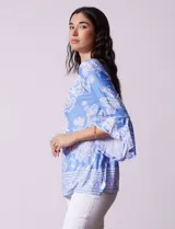 Blusa color salmón con estampado floral blanco, cuello redondo con abertura y mangas 3/4 acampanadas.