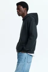 Canguro negro H&M con capucha, bolsillo frontal tipo canguro y diseño gráfico de Fender en el pecho.