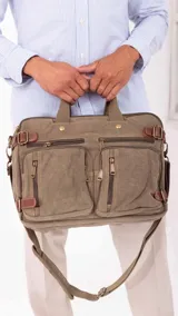Mochila porta notebook color verde oliva de tela canvas con detalles en cuero marrón. Tiene múltiples bolsillos con cierre y correas ajustables.