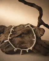 Collar de perlas de diversas formas, tamaños y matices, con diseño irregular y cierre metálico.