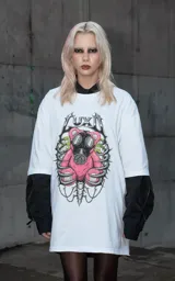 Remera blanca de corte oversize con estampa frontal de un oso de peluche rosa con máscara de gas, rodeado por una estructura ósea.