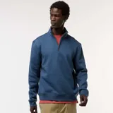 Buzo azul con cuello alto y cremallera parcial.