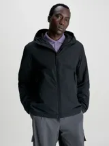 Campera negra con capucha, cierre de cremallera, bolsillos delanteros con cremallera y puños elásticos. Confeccionada con nailon arrugado reciclado y forro de malla de poliéster reciclado. Aislante de poliéster reciclado REPREVE® e insignia con el logo de goma de Calvin Klein en la manga.