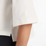 Remera de corte cropped y mangas cortas, confeccionada en tejido de punto de algodón. Presenta un estampado gráfico frontal con el logo de New Balance con diseño de encaje.