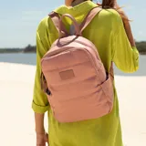 Mochila de nylon acolchada en color rosado, con diseño capitoneado horizontal. Cuenta con cierre superior, bolsillo frontal con cierre, bolsillos laterales y correas regulables de cinta. Incluye asa superior de mano y etiqueta frontal con logo.