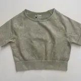 Remera deportiva verde oliva de corte cropped, con cuello redondo y mangas cortas.