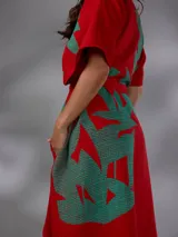Capullo o kimono de paño 100% algodón, color rojo con estampado exclusivo en tono verde, de morfología amplia y envolvente, con bolsillos laterales y cinto independiente para ajustar la cintura.