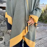 Ruana de material símil cachemira, de diseño bicolor en tonos gris y lila con bandas anchas en los bordes.