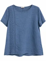 Blusa azul jean de manga corta y cuello redondo, con detalles de alforzas y bordados verticales en el lateral derecho y terminaciones con volados sutiles en las mangas.