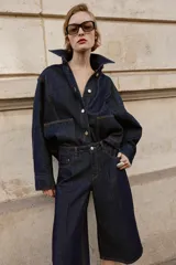Bermuda de tiro alto confeccionada en denim azul oscuro, con diseño de pernera ancha, cinco bolsillos y cierre frontal con cremallera y botón.