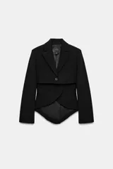 Blazer asimétrica de Zara Woman Collection, confeccionada con mezcla de lana. Presenta cuello solapa, manga larga con botones, cierre frontal con un botón y bajo asimétrico con abertura. Incluye forro interior a tono.